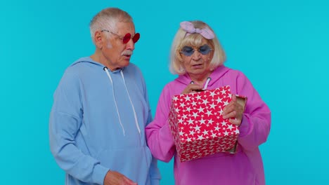 el abuelo mayor la abuela desempaquetando el regalo, expresando decepción, aversión al mal regalo