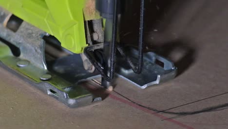 close-up of electric jigsaw in action, men's hand cutting up wood board with a jigsaw in slow motion