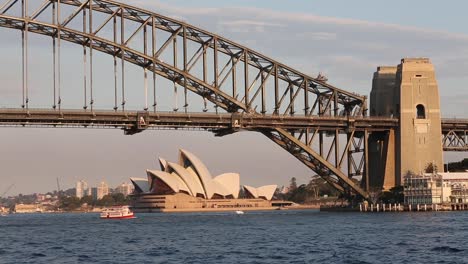 View of Sydney Harbor Bridge and Sydney Opera House in Perfect late afternoon light with boating traffic on the water. View from Blues Point. Historic Wooden Ferry "Radar" Dwarfed by massive bridge