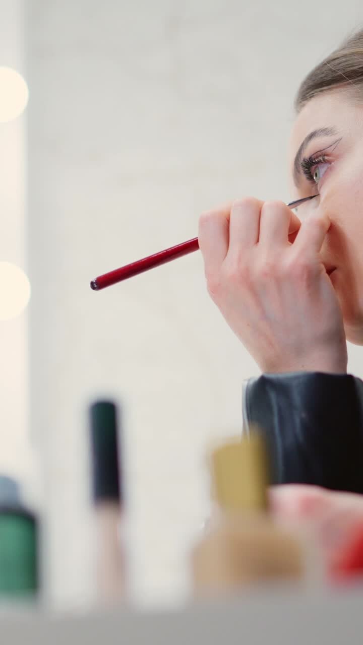 Donna che applica l'eyeliner con un pennello da trucco