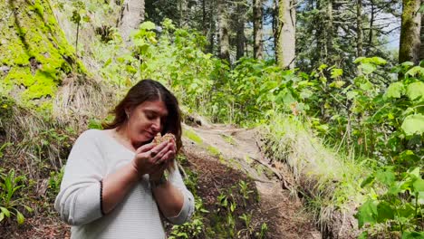 curvy, no makeup, natural woman smells the freshness of a chunk of baby forest mushrooms