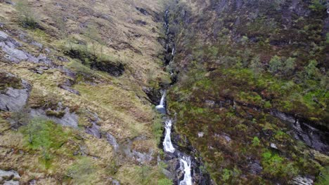 aerial view of a stunning waterfall cascading down a rocky mountainside in scotland