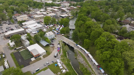 Vista-Aérea-De-Cabinas-Y-Personas-Reunidas-Junto-Al-Arroyo-Sager-Durante-El-Festival-Dogwood-En-Siloam-Springs,-Arkansas