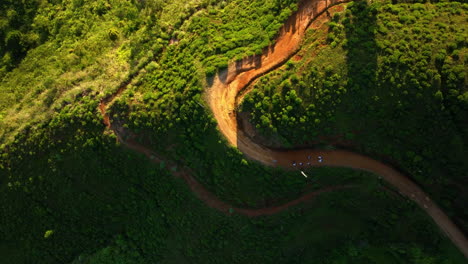 Aerial-view-above-a-group-of-people-walking-on-a-highland-road,-sunset-in-Sri-Lanka