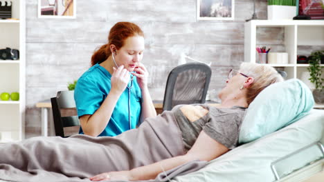 female nurse listening to old lady heartbeats