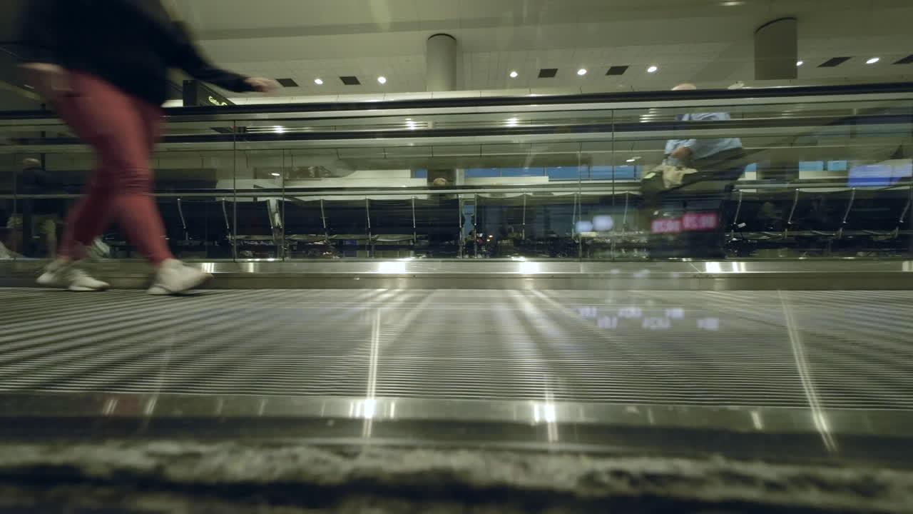 люди проходят мимо на движущейся дорожке в аэропорту