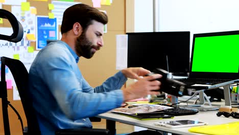 diseñador gráfico masculino mirando fotos en la cámara