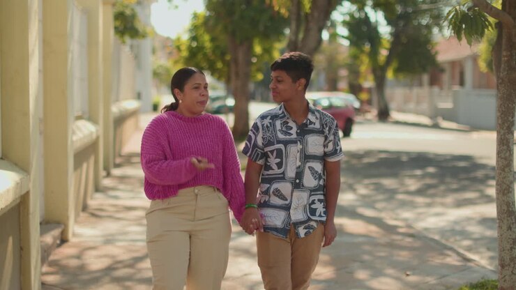 A woman and a young boy share affectionate moments walking and hugging on a sunny city street