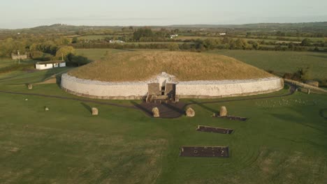 ancient stone tomb on a grassy hill in ireland lit by warm sunrise overlooking the river boyne