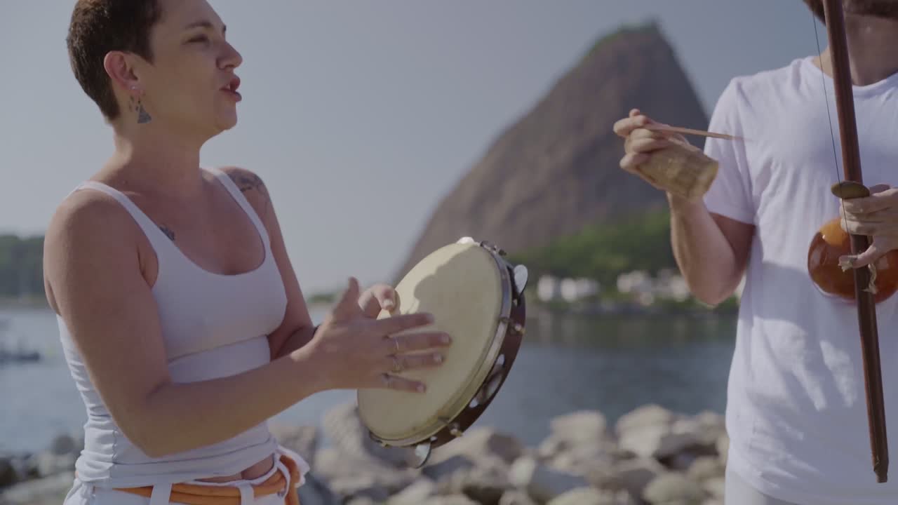 Joyful Brazilian musicians playing berimbau and tambourine outdoors