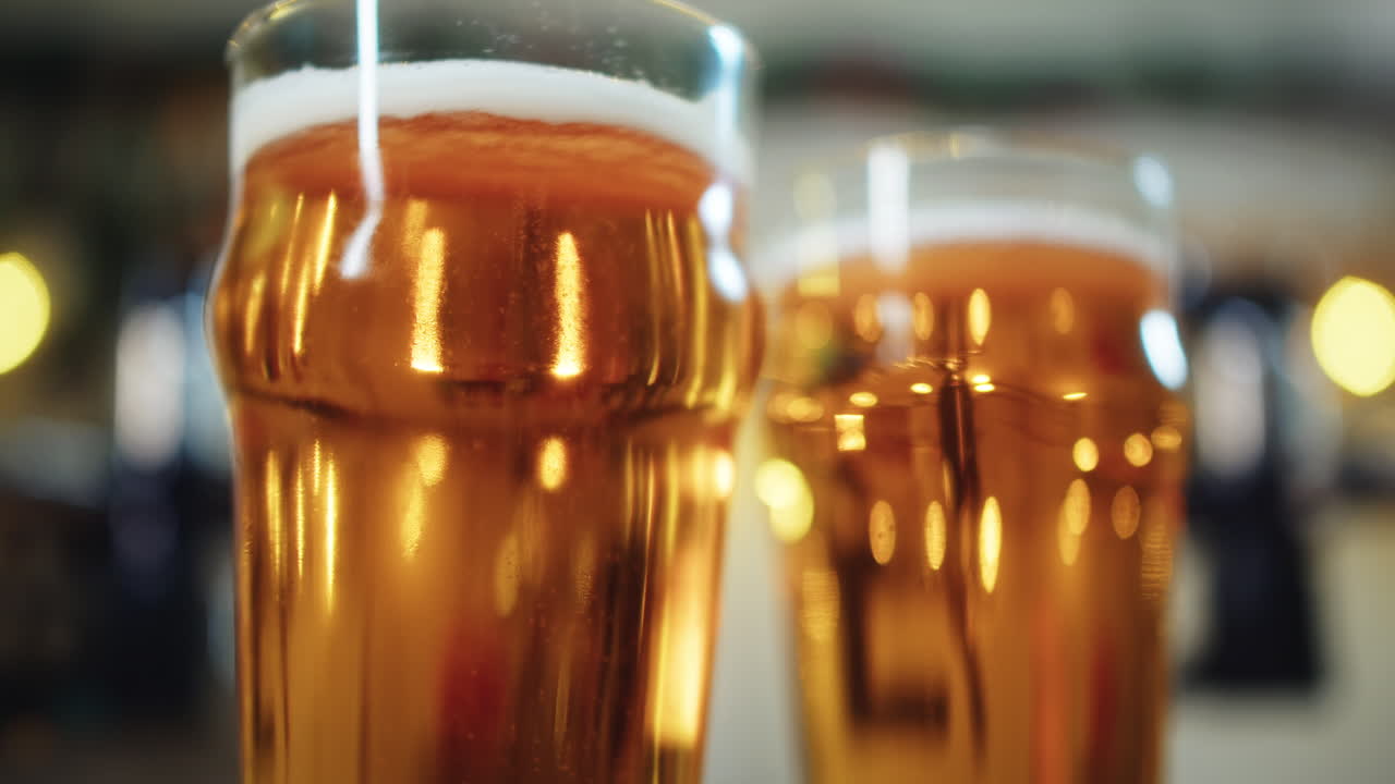Birra dorata che riempie due bicchieri sul bancone di un bar
