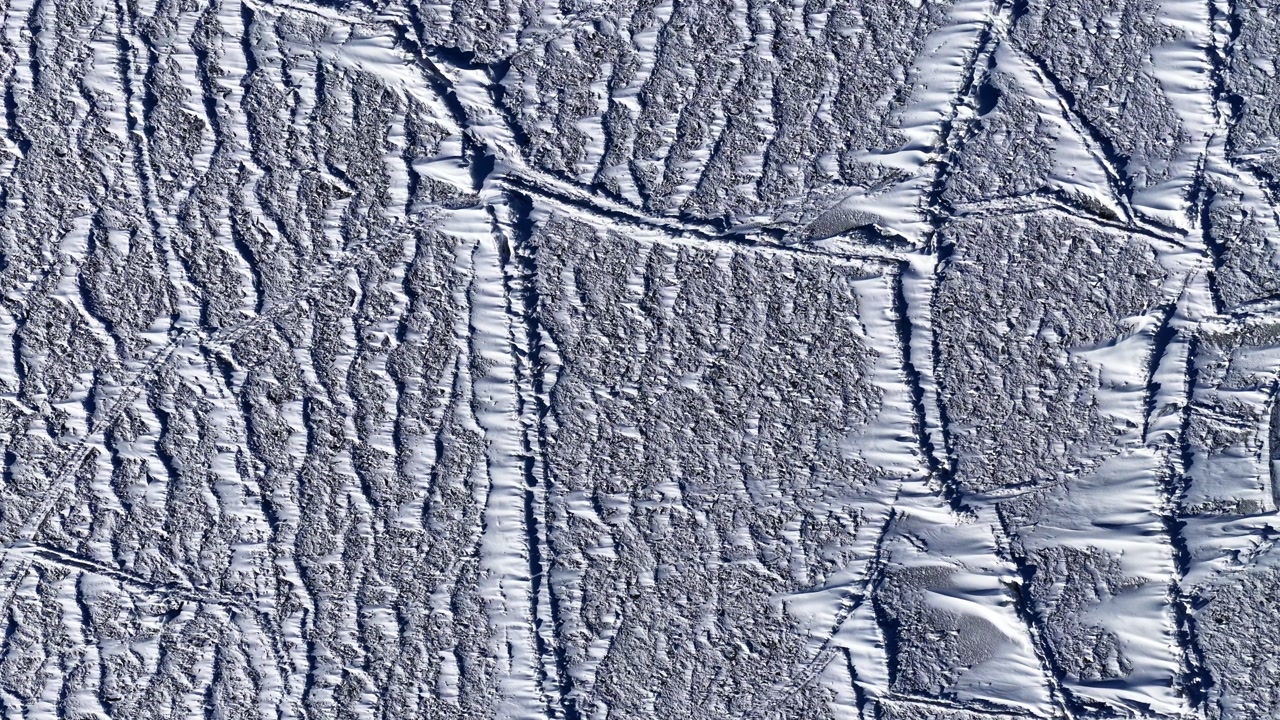 Aerial view of icy landscape with patterns in winter sunlight