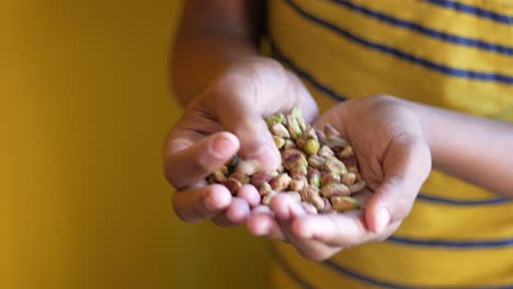 child holding a handful of pistachios