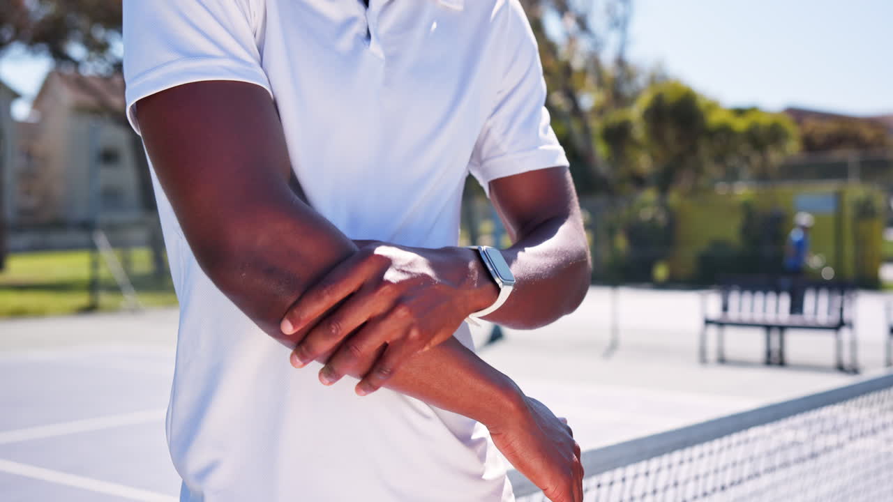 Uomo che si strofina il gomito dolorante su un campo da tennis