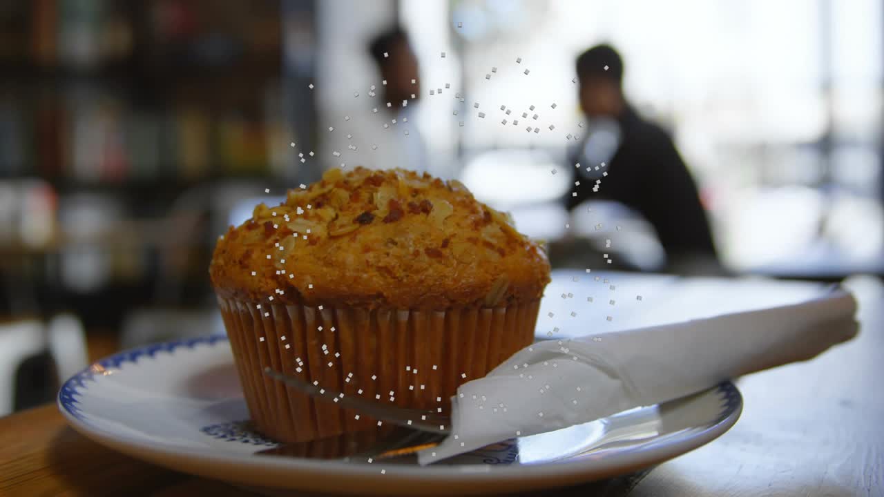 Scintilla iniziale che fa cadere i granelli di zucchero, ricoprendo il muffin mentre la telecamera scorre rivelando il tovagliolo