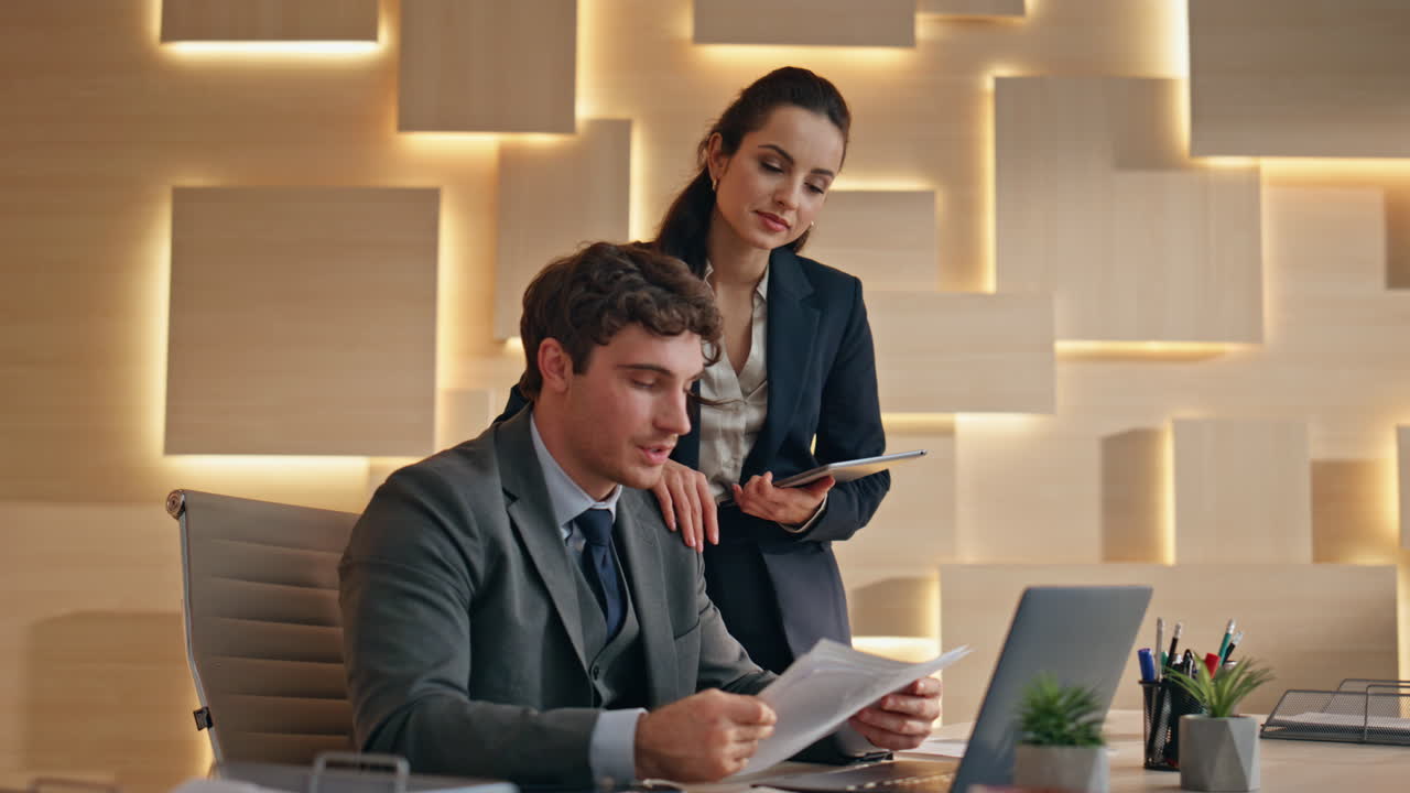 Two colleagues video calling laptop greeting in office closeup. Couple talking