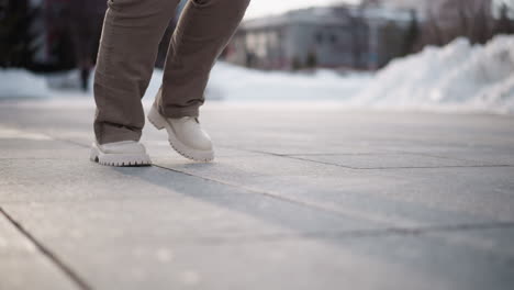 leg view of young lady exercising outdoors moving legs laterally on tiled pavement under winter sky capturing dynamic fitness routine energy and casual style in urban park setting background