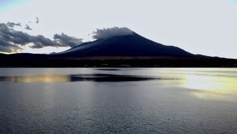 Mount-Fuji-at-dusk-with-its-reflection-on-the-lake,-clouds-above