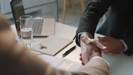 hombres de negocios multiétnicos estrechando la mano en la mesa de la oficina