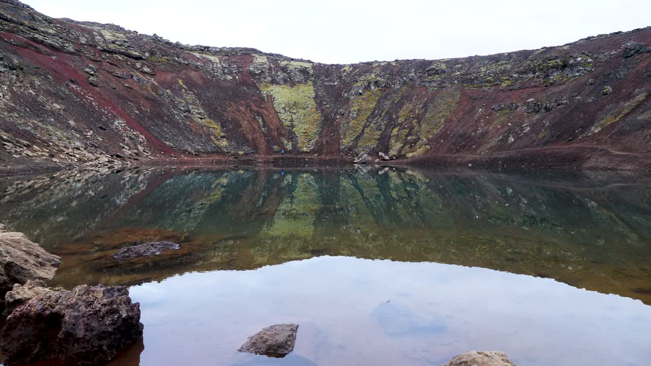 tranquilo lago de cráter volcánico en islandia con pendientes escarpadas y coloridas y un claro reflejo en el agua