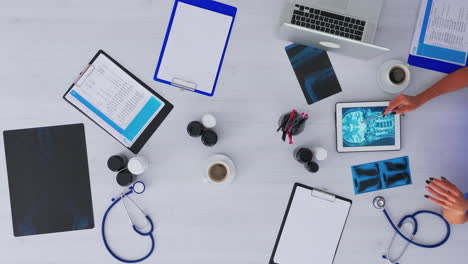 Nurse-analysing-human-brain-using-tablet-on-flatlay