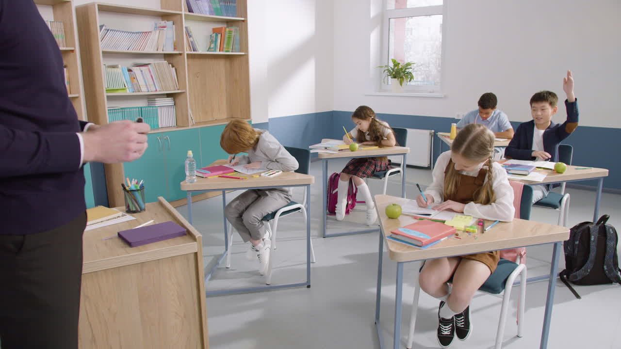 группа многонациональных учеников пишет в тетради, затем мальчик встает и идет к доске