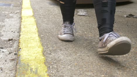 Beat-up-shoes-and-outfit-walking-along-the-sidewalk-of-an-industrial-place