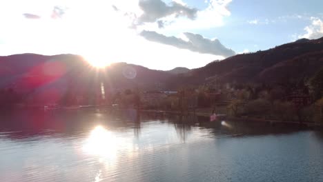 Aerial-Over-Lake-Endine-With-Sun-Shining-Through-Hillside-And-Reflecting-Off-Lake-Surface