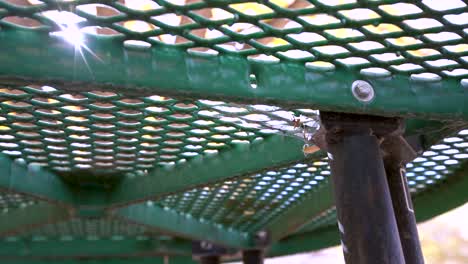 Slow-motion-shot-of-dirty-spider-web-waving-in-the-wind-under-picnic-table-with-sun-shining-through