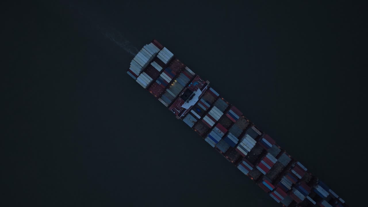 Maritim logistik fanget ovenfra, containerskib på Elben i skumringen.