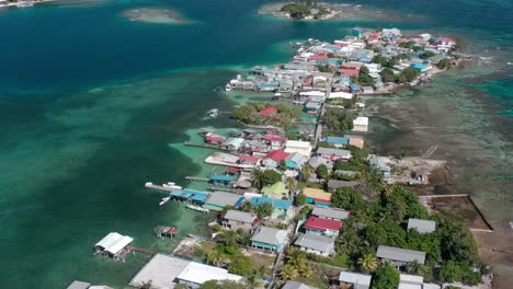 aerial establishing overview of fishing village and docks built around reef flats in utila honduras