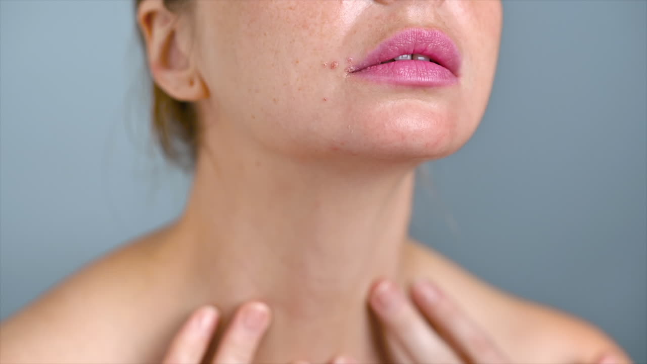 A young caucasian woman is moisturizing skin with cosmetic oil while doing facial and neck massage. Slow motion