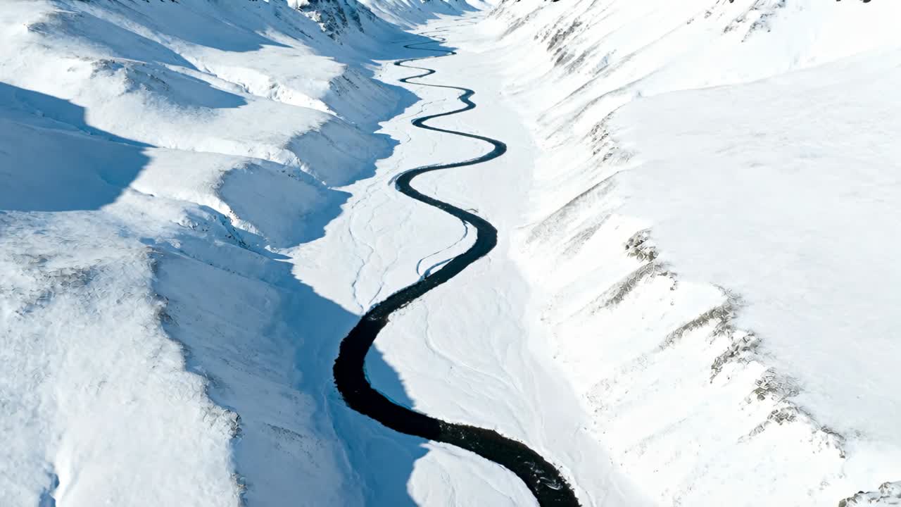 Gliding aerial camera pulling forward along snowy valley to reveal winding dark river meanders