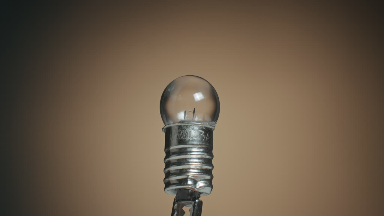 primer plano de una bombilla de filamento de tungsteno y una foto macro de componentes electrónicos en la mesa giratoria