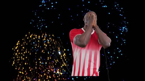 animation of fireworks over african american male soccer player smiling