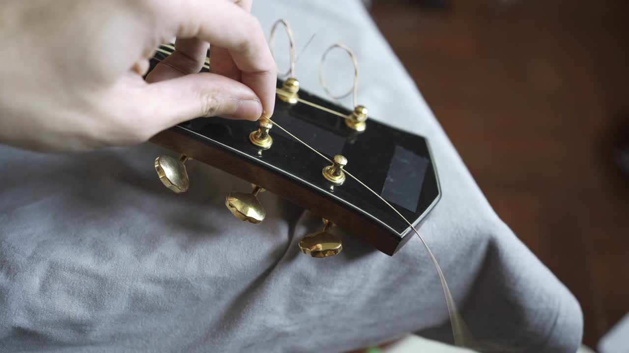Put a new guitar string on an acoustic guitar