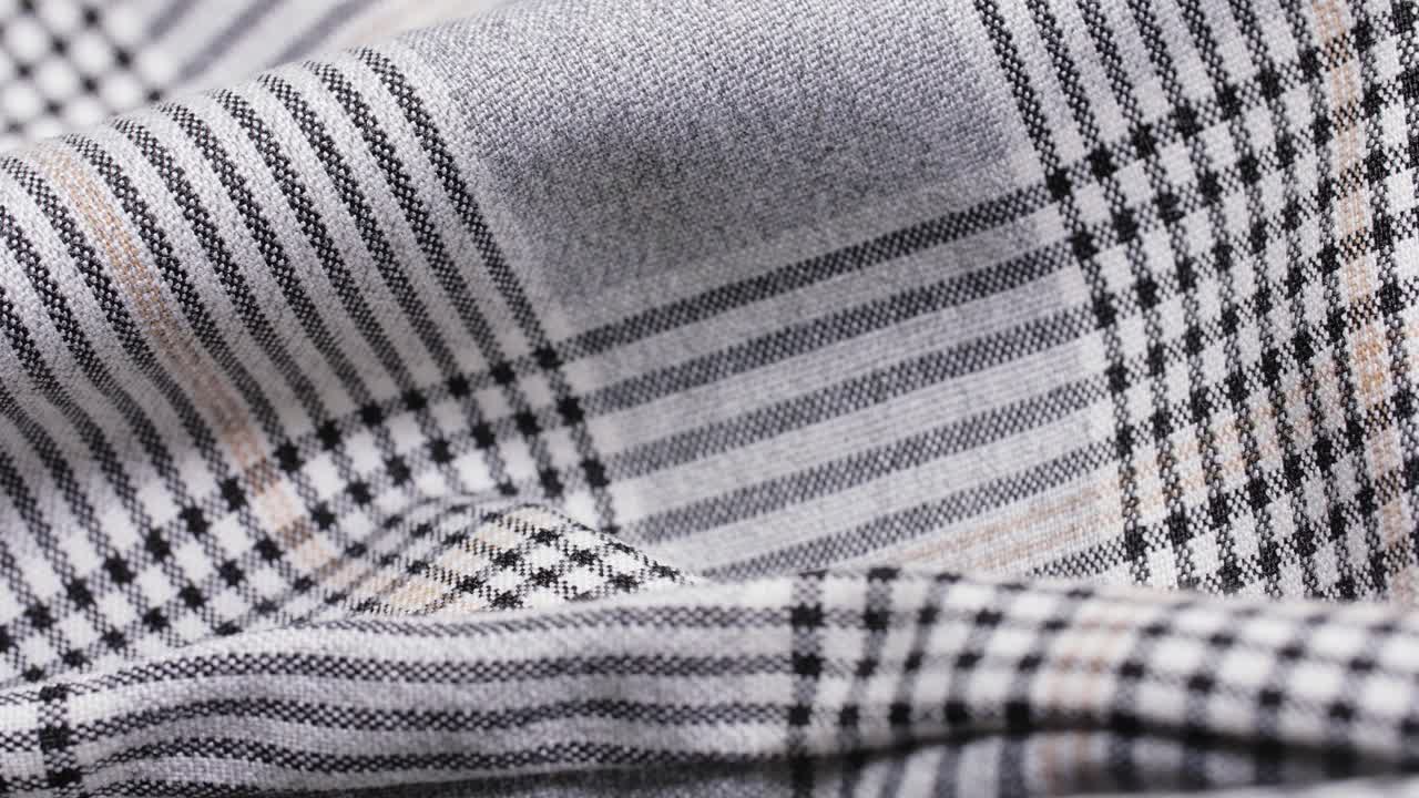 Black and grey glen plaid trouser fabric shows soft folds in a slow macro pan