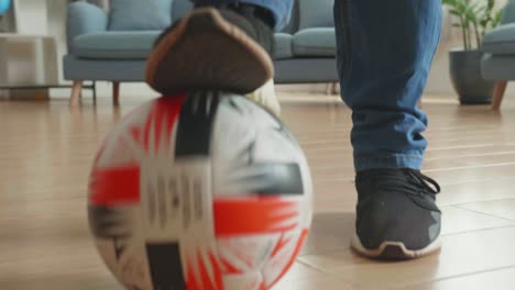feet man playing soccer ball in living room