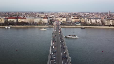 aerial view of traffic at bridge above river danube during sunset at budapest with the city in the background