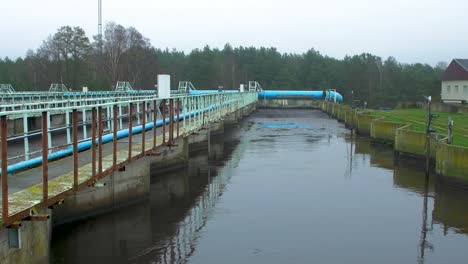 City-sewage-treatment-plant,-grey-wastewater-recycling,-tank-for-sedimentation-and-filtration-of-water,-waste-and-pollution-management-theme,-overcast-autumn-day,-wide-shot