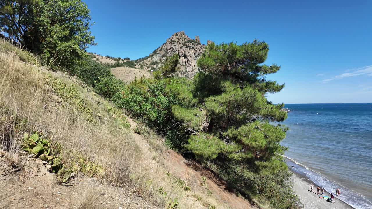 Scenic coastal landscape with mountains, pebble beach, and blue sea under clear skies
