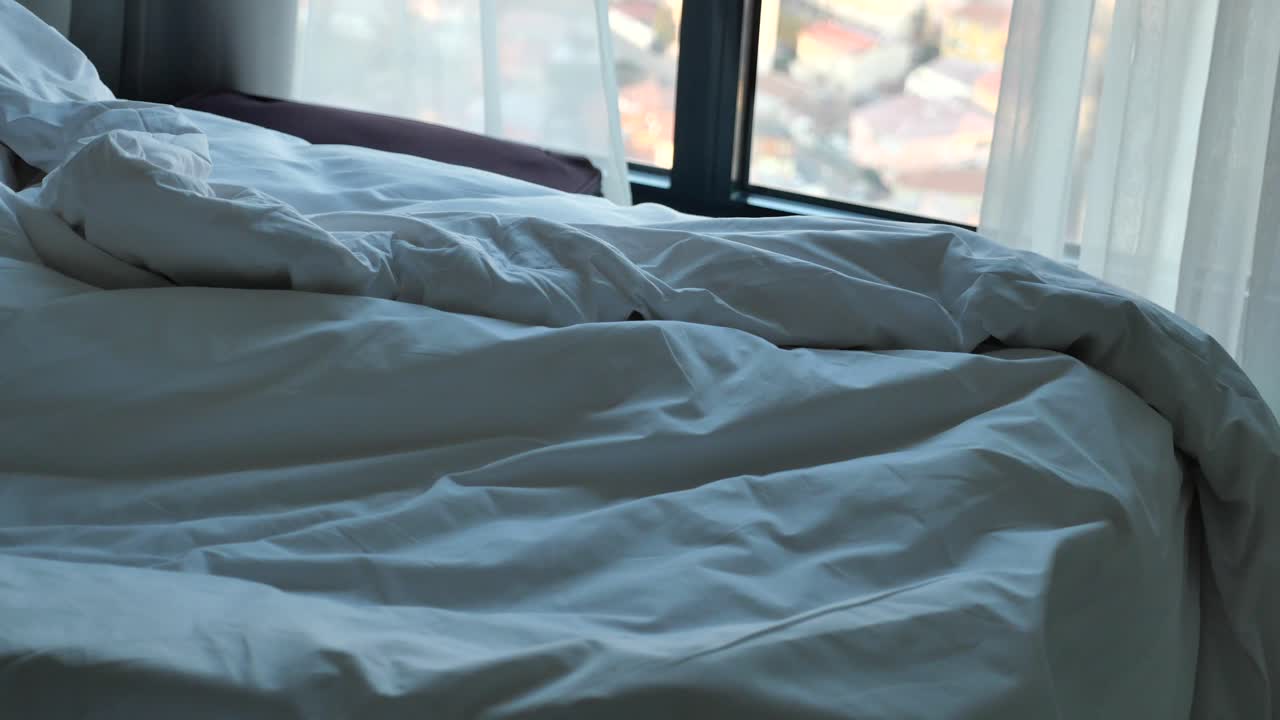 cama sin hacer con vista a la ciudad