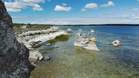 Aerial-view-of-quiet-beach-with-huge-rock-formations,-zooming-shot