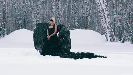 model-in-phoenix-costume-with-black-wings-in-winter-forest