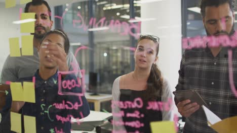 diverse group of work colleagues brainstorming writing notes on glass wall