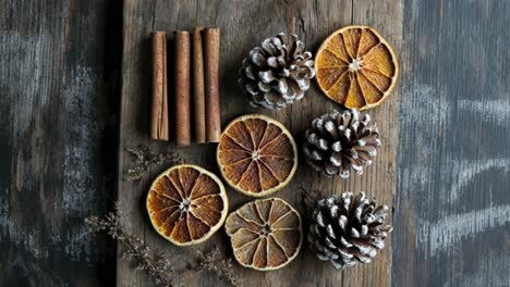 rebanadas de naranja secas, palitos de canela y conos de pino en una tabla de madera
