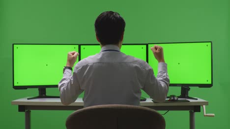 hombre celebrando frente a una pantalla verde de triple monitor