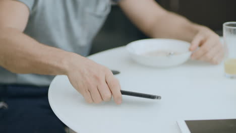 Closeup-man-hand-getting-good-news-eating-breakfast.