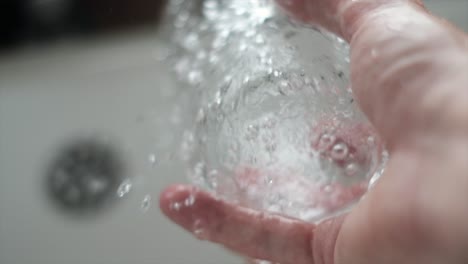 super slow motion shot of water cascading into a clear glass. cinematic slow motion of water streaming into a glass