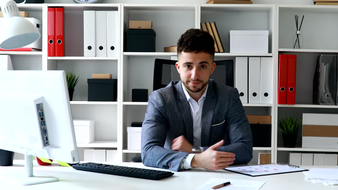 giovane uomo giacca grigia seduto a tavolo in ufficio bianco e offrendo documenti